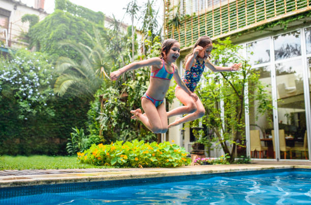 istock Fun Sisters Jumping into Family Swimming Pool 1190129429