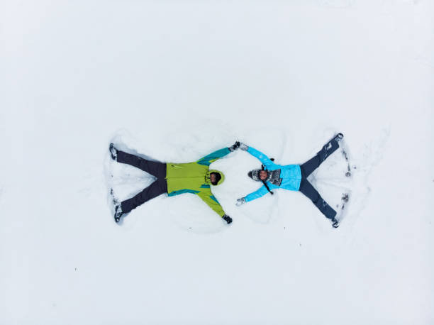 istock couple having fun making snow angel 1190129951
