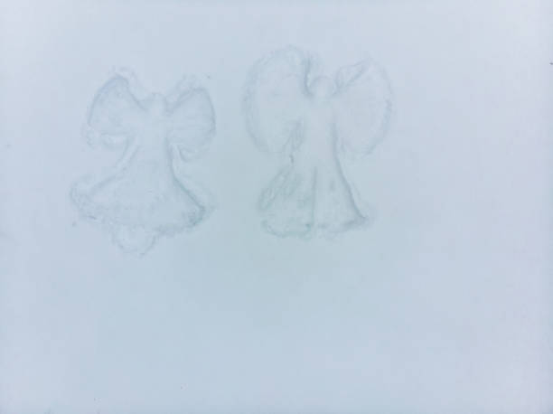 Young beautiful woman in a gray jacket, light pants, boots makes a snow angel in the snow, a view from a drone. Copy space, banner. Snow fun, entertainment.