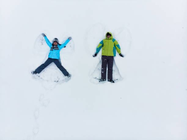 istock couple having fun making snow angel 1190129961