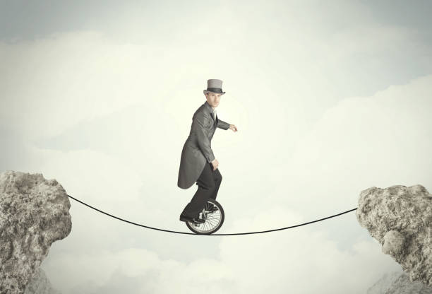 istock Brave business man riding an mono cycle between cliffs 1190130023