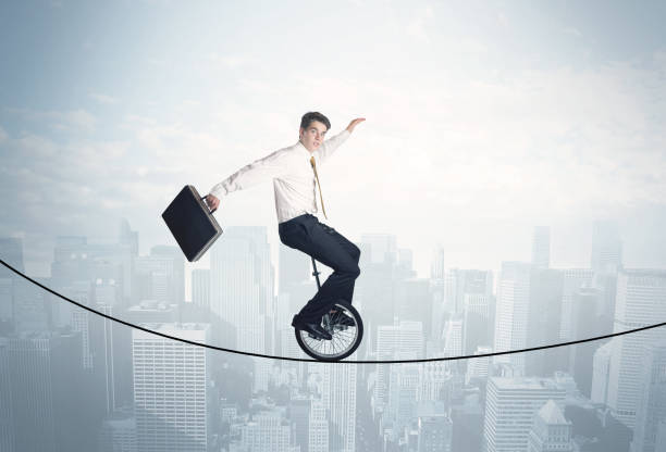 istock Brave guy riding a monocycle on a rope above cityscape 1190130213