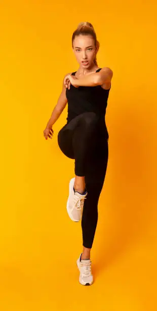 Cardio Workout. Determined Girl Jumping Exercising Over Yellow Studio Background. Full Length