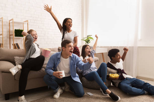 Emotional football fans. Teens watching match at home Emotional football fans. Teens watching match at home and celebrating victory, free space tv game stock pictures, royalty-free photos & images