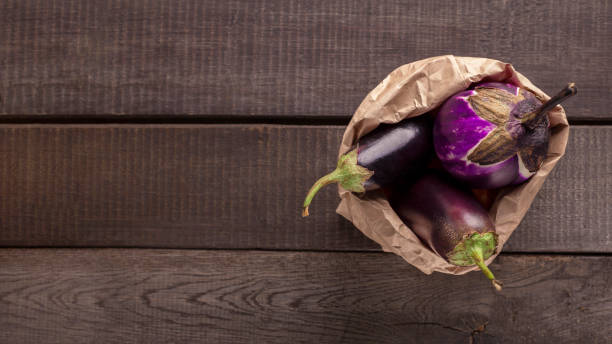 istock Fresh eggplant inside paper package on wooden background 1190132440