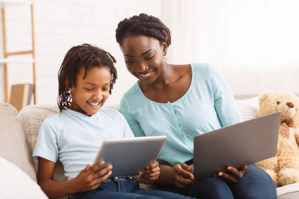 afro mom and daughter doing school homework - laptop women child digital tablet imagens e fotografias de stock