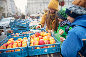 Three kids buying apples on farmer's market in Brno