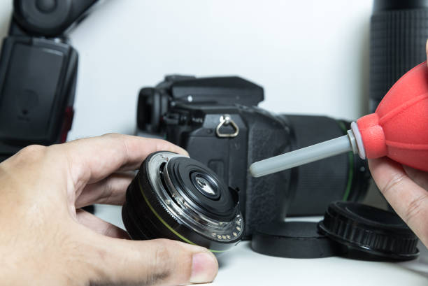 DSLR camera lens cleaning by blowing dust of the lens DSLR camera lens cleaning by blowing dust of the lens Live Video Capture Solutions stock pictures, royalty-free photos & images