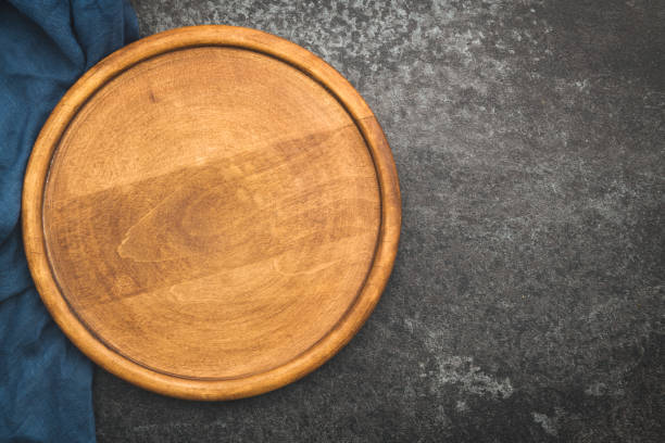 istock Round empty wooden pizza board on dark concrete background 1190135610