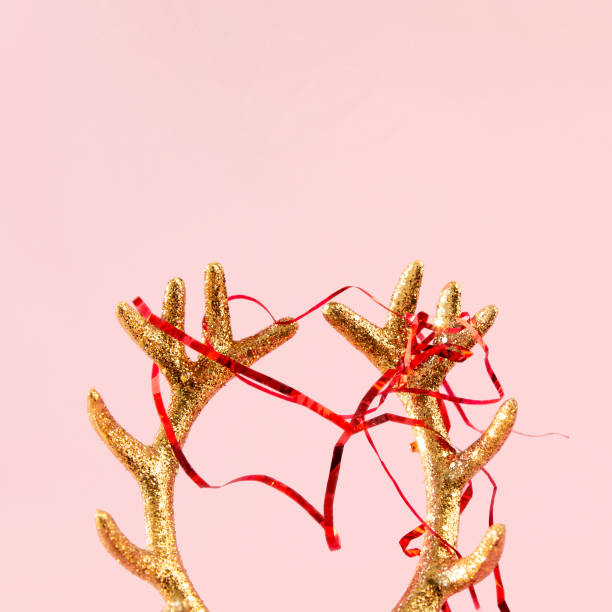 golden deer horns with red newfoot tinsel on pink background. xmas composition in minimal style - reindeer christmas decoration gold photography imagens e fotografias de stock