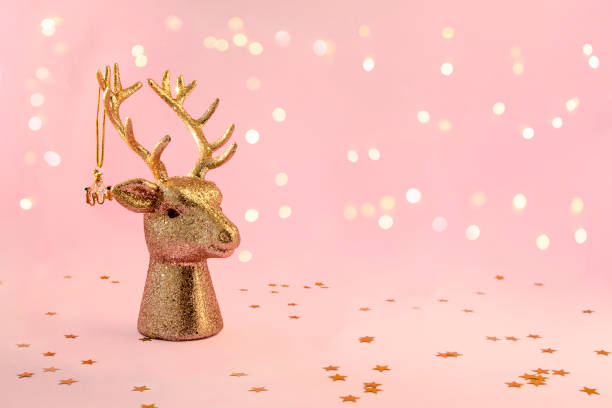 xmas композиция в минимальном стиле - золотая голова оленя с рождественской безделушкой висит на рогах на розовом фоне с новогодними огнями, � - reindeer christmas decoration gold photography стоковые фото и изображения