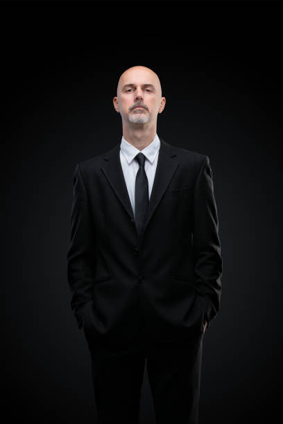 one arrogant mature man in black suit on black background arrogant looking man in black suit with tie isolated on black background could be used as doorman bouncer fbi bouncer security staff stock pictures, royalty-free photos & images