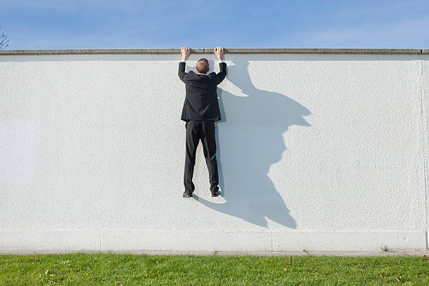 geschäftsmann klettern über mauer - moving up looking men people stock-fotos und bilder