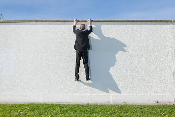 businessman climbing en pared - hombre colgado fotografías e imágenes de stock