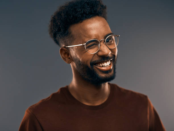 You got me right there Studio portrait of a handsome young man winking while standing against a grey background winking stock pictures, royalty-free photos & images