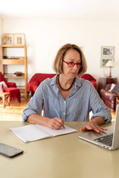 Femme aîné d'âge moyen travaillant à la maison utilisant l'ordinateur - Photo