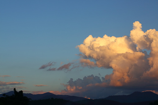 landscape image, large cloud on blue sky above mountain hill