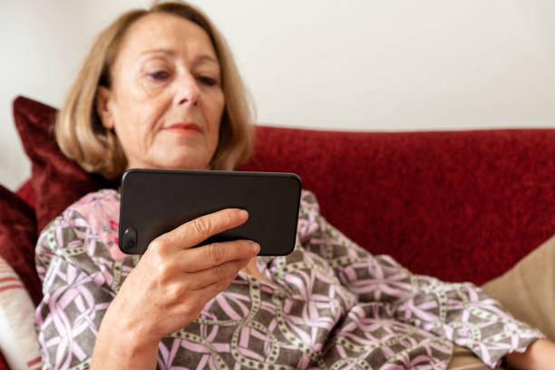 istock Elegant mature woman using smartphone while sitting on the sofa 1190141395