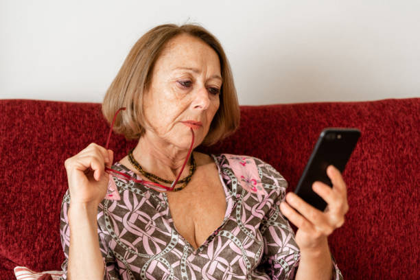 istock Elegant mature woman using smartphone while sitting on the sofa 1190143058