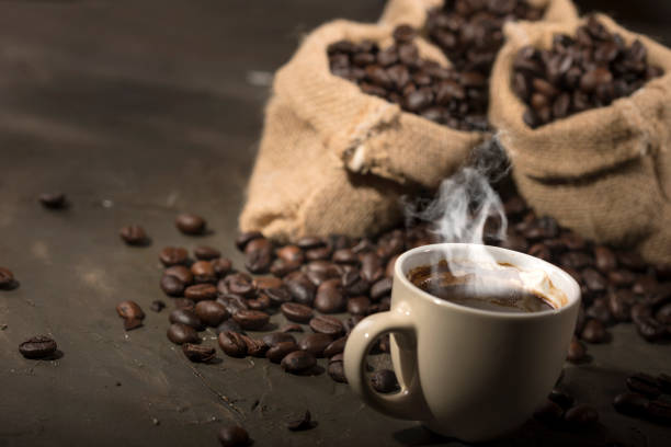 istock Coffee cup and sacks with coffee beans on a black table. 1190144131