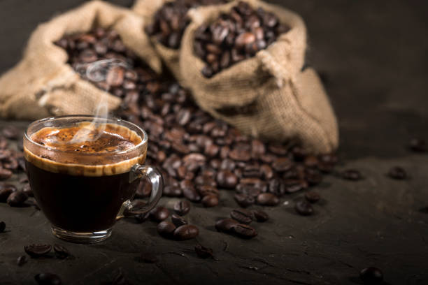 istock Coffee cup and sacks with coffee beans on a black table. 1190144147