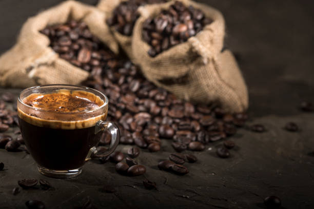 istock Coffee cup and sacks with coffee beans on a black table. 1190144153