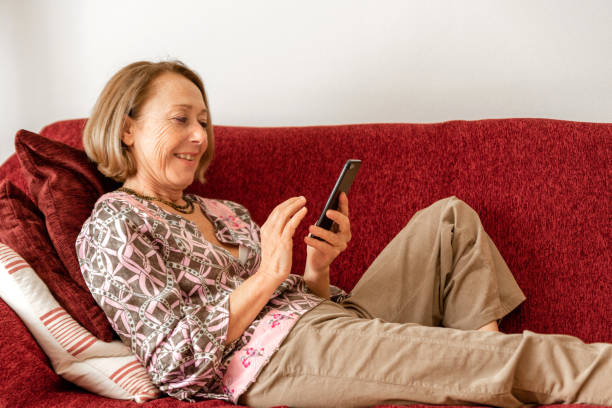 istock Elegant mature woman using smartphone while sitting on the sofa 1190144175