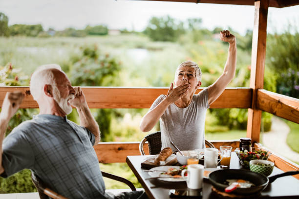 istock Senior couple yawning during breakfast time on a terrace. 1190145985