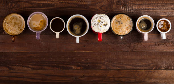 Lots of coffee in different cups on old wooden table with copy space