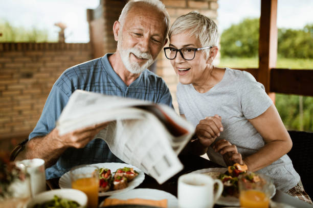 istock Happy senior couple reading newspapers during breakfast on a terrace. 1190146315