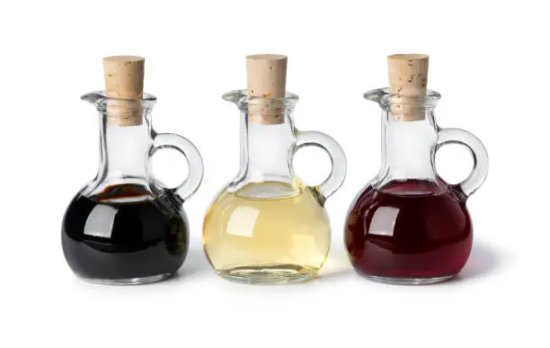 Three glass bottles with different types of vinegar isolated on white background