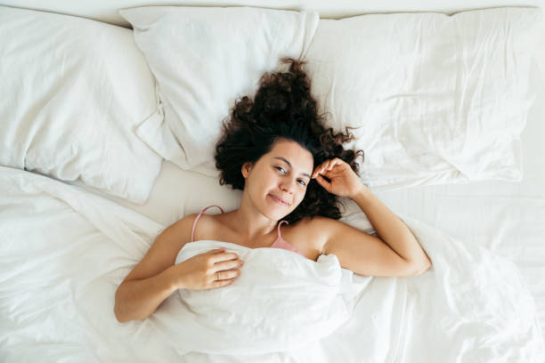 istock young pretty woman in bed with white sheets bright light 1190147574