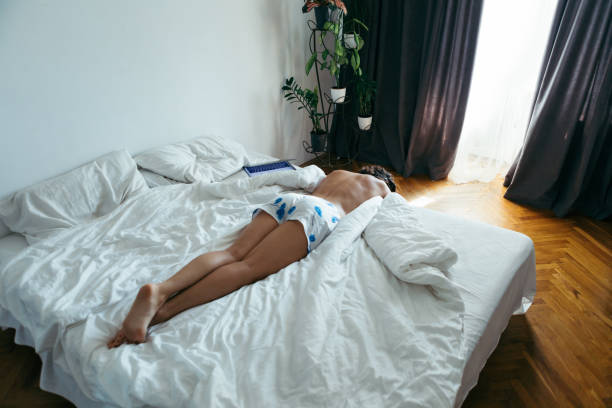 istock woman laying on the bed white sheets light from window with curtains 1190147611