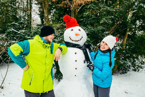 istock couple posing near big snowman in red hat 1190147706