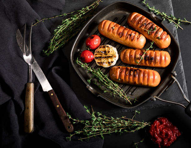 istock Sausages with thyme and vegetables in a pan on black background. 1190148412