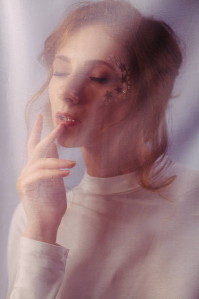 istock Young beautiful redhead girl behind a light transparent fabric 1190151834