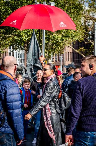 Amsterdam, Holland, September 2018 too many tourists visiting the city of Amsterdam proofs this long female guide with red umbrella and long leather jacket and sunglasses