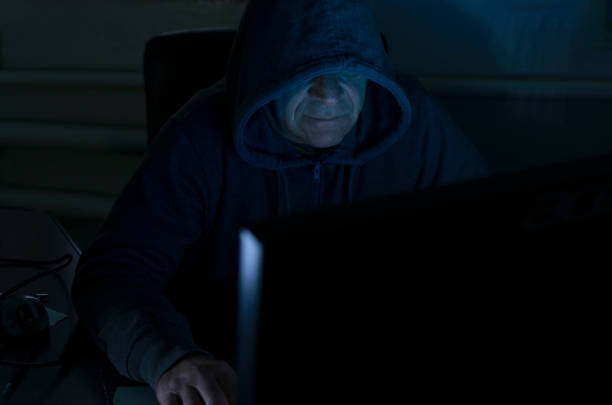 istock Spy sits at the computer at dark night. Blue light from screen on the hacker`s face 1190153696