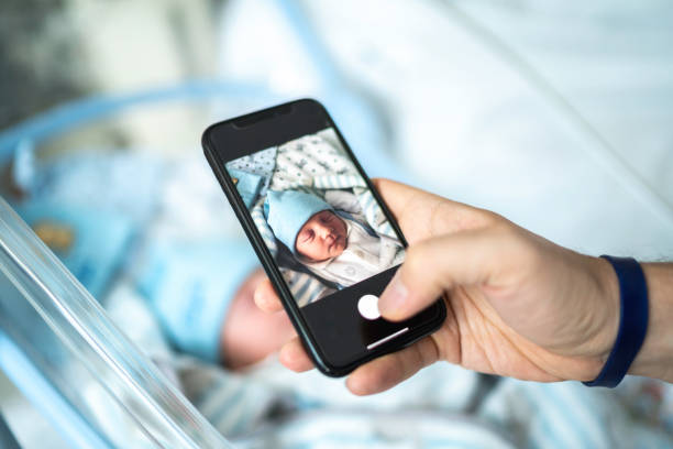 vater fotografiert sein neugeborenes im krankenhaus - phone cradle stock-fotos und bilder
