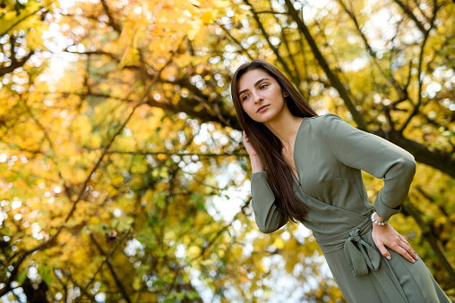 Female portrait. Brunette woman portrait in autumn park wearing olive dress
