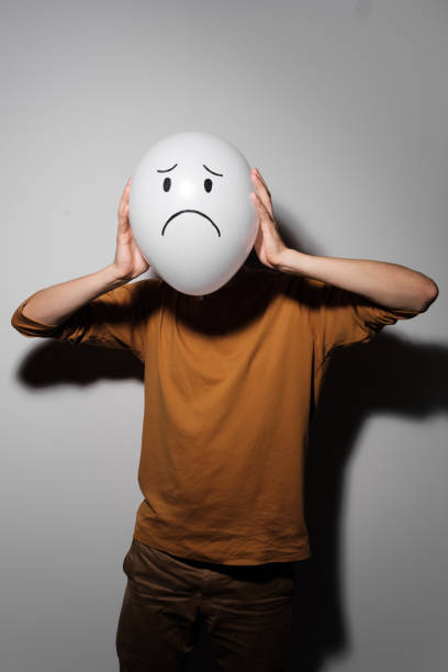 istock A man holding white balloon with sad smile face emotion instead of head. Negative Thinking concepts. 1190157884