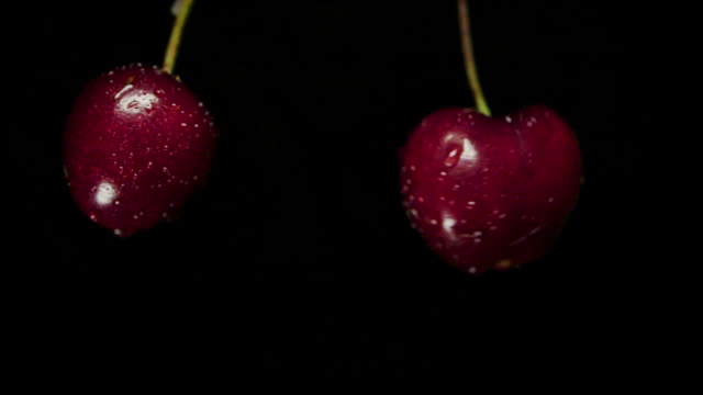 Slow motion shot of Two cherry crashing black background