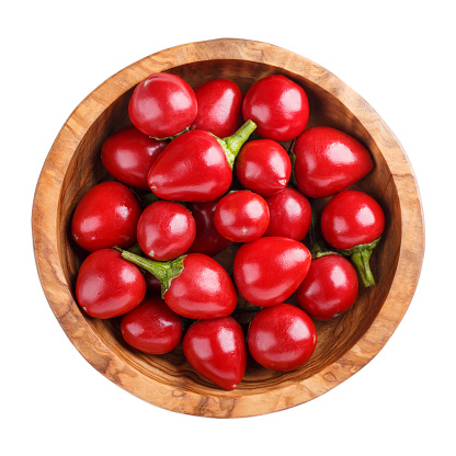 Red round chili peppers, hot hilli pepper large cherry  in wooden bowl isolated on white. Top view.