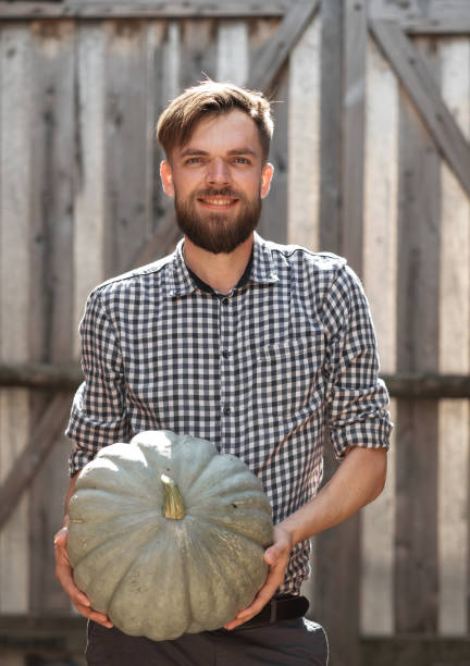 istock farmer holds a big pumpkin in his hands. 1190161409