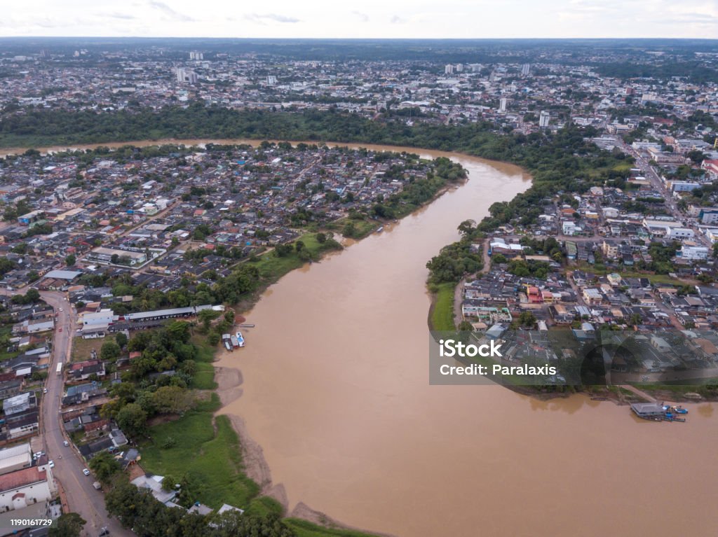 Aerial drone view of Acre river curves in the amazon and Rio Branco city center buildings, streets on cloudy winter day. Concept of environment, ecology, global warming, climate change and travel. Acre - Brazil Stock Photo