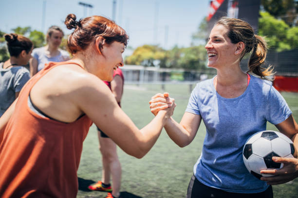 Women soccer players shaking hands Group of women, female soccer players together outdoors on soccer field, two women shaking hands. football player girlfriend stock pictures, royalty-free photos & images