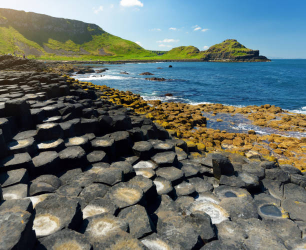 calzada de los gigantes, un área de piedras de basalto hexagonal, condado de antrim, irlanda del norte. famosa atracción turística, patrimonio de la humanidad de la unesco. - carretera sobre agua fotografías e imágenes de stock