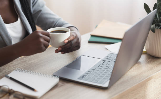 istock Afro businesswoman having coffee while working on laptop in office 1190166120