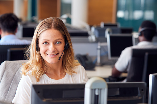 Portrait Of Businessman Wearing Telephone Headset Working In Customer Services Department