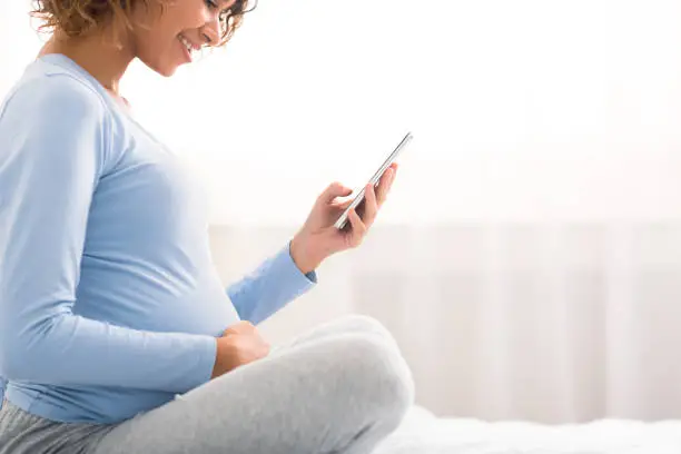 Photo of Pregnancy apps concept. Expectant woman using cellphone